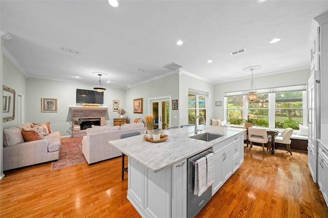 kitchen with light hardwood / wood-style floors, white cabinetry, a kitchen island with sink, and sink