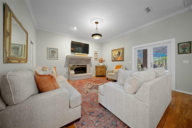 living room featuring dark wood-type flooring, a brick fireplace, crown molding, and french doors