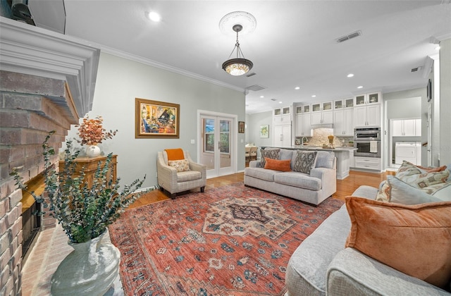 living room with french doors, crown molding, light hardwood / wood-style floors, and a fireplace