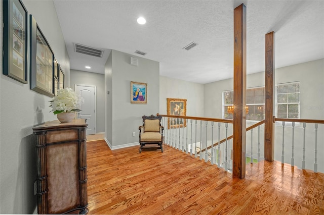 hallway with a textured ceiling and wood-type flooring