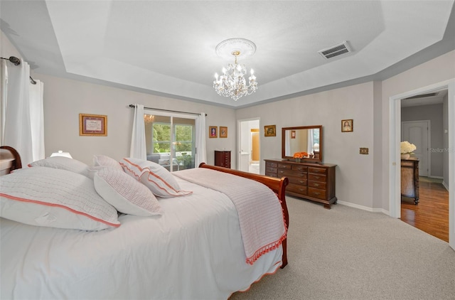 carpeted bedroom featuring an inviting chandelier and a raised ceiling