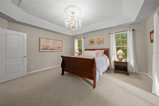 bedroom with a chandelier, a tray ceiling, and light colored carpet