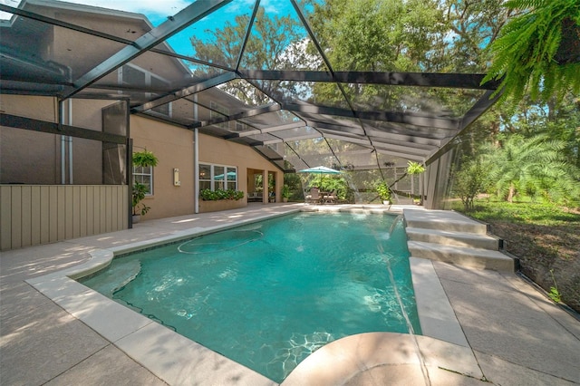 view of pool with a patio, pool water feature, and glass enclosure