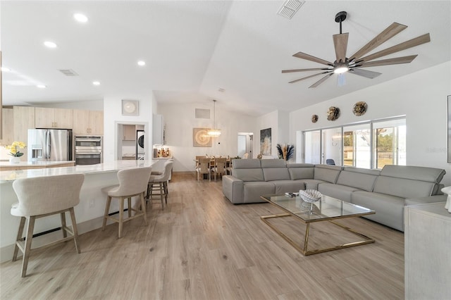 living room with ceiling fan, vaulted ceiling, and light wood-type flooring