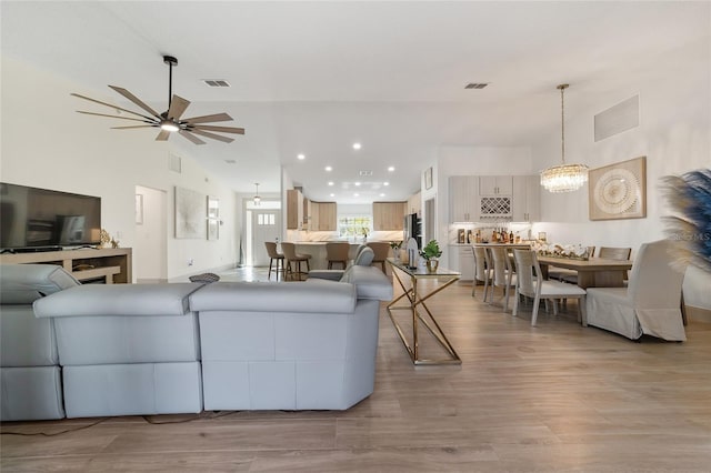 living room with light hardwood / wood-style flooring, high vaulted ceiling, and ceiling fan with notable chandelier