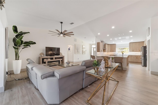 living room with lofted ceiling, light hardwood / wood-style floors, and ceiling fan