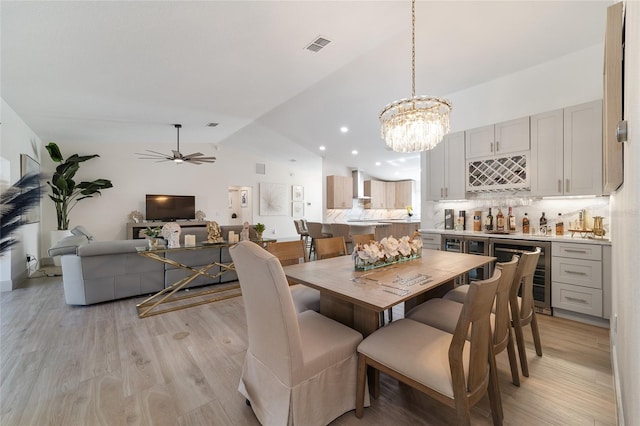 dining space with light hardwood / wood-style floors, lofted ceiling, beverage cooler, and ceiling fan with notable chandelier