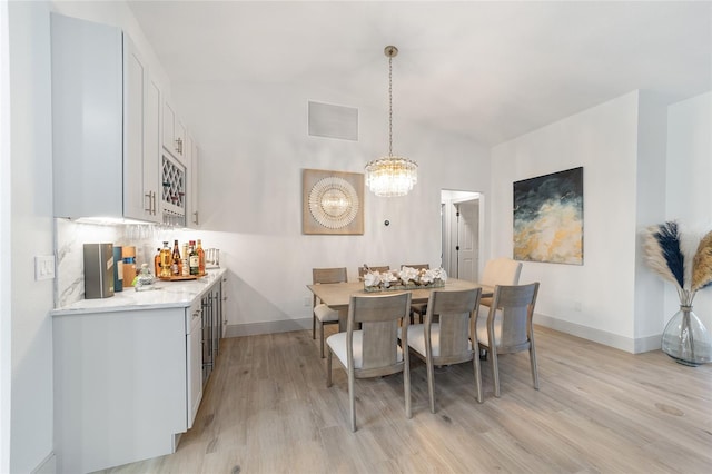 dining area featuring light hardwood / wood-style flooring and an inviting chandelier