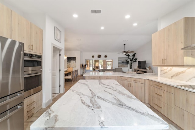 kitchen with light stone counters, stainless steel appliances, and light brown cabinetry