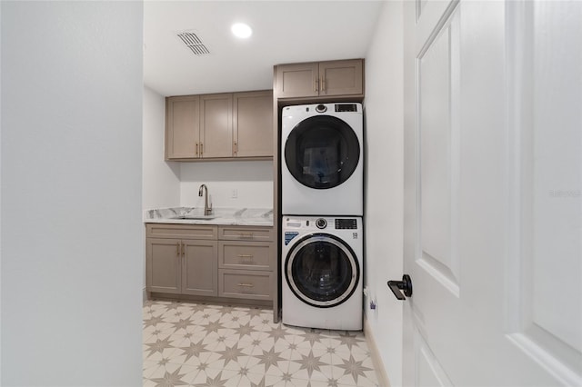 laundry area featuring cabinets, stacked washer / dryer, and sink