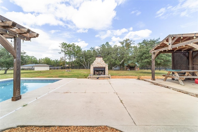 view of pool with a patio, an outdoor stone fireplace, and a yard