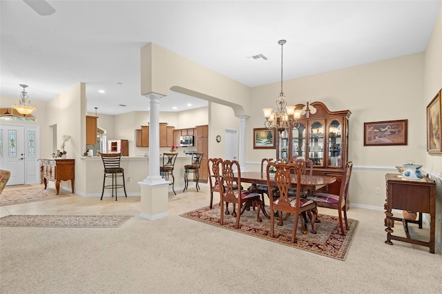 dining space with light carpet, an inviting chandelier, and decorative columns