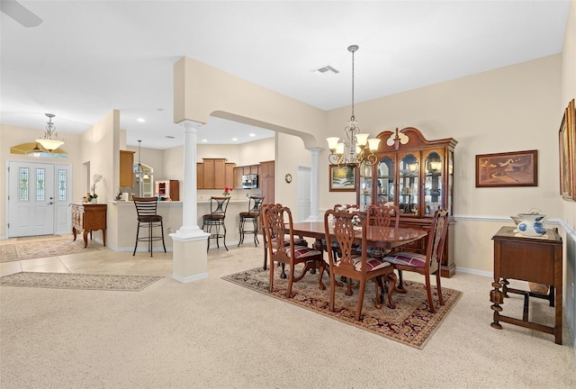 carpeted dining space with an inviting chandelier and decorative columns