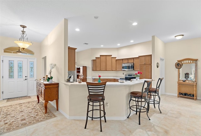 kitchen featuring kitchen peninsula, a breakfast bar, light tile patterned flooring, decorative light fixtures, and appliances with stainless steel finishes