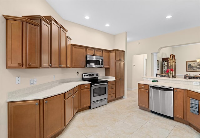 kitchen featuring decorative columns, light tile patterned flooring, and stainless steel appliances