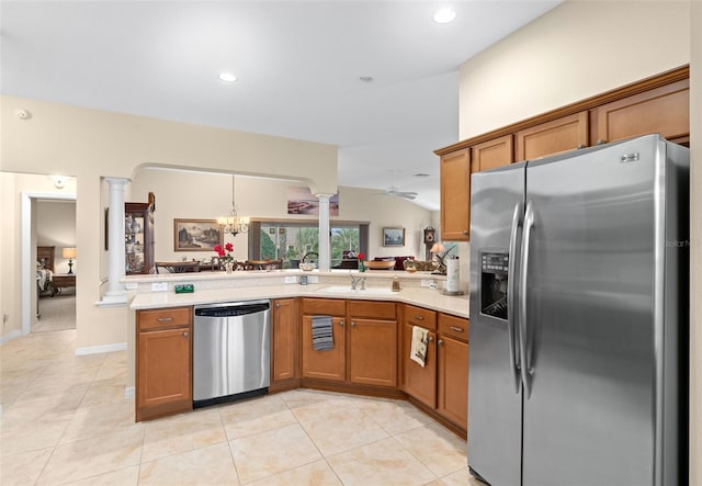 kitchen featuring kitchen peninsula, decorative columns, vaulted ceiling, appliances with stainless steel finishes, and ceiling fan with notable chandelier