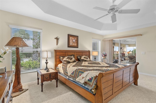 bedroom with light carpet, ceiling fan, and a tray ceiling