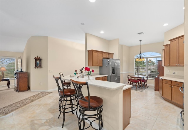 kitchen with a healthy amount of sunlight, a kitchen bar, stainless steel fridge, and decorative light fixtures