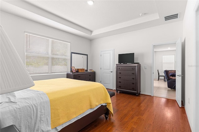 bedroom with a tray ceiling and hardwood / wood-style floors