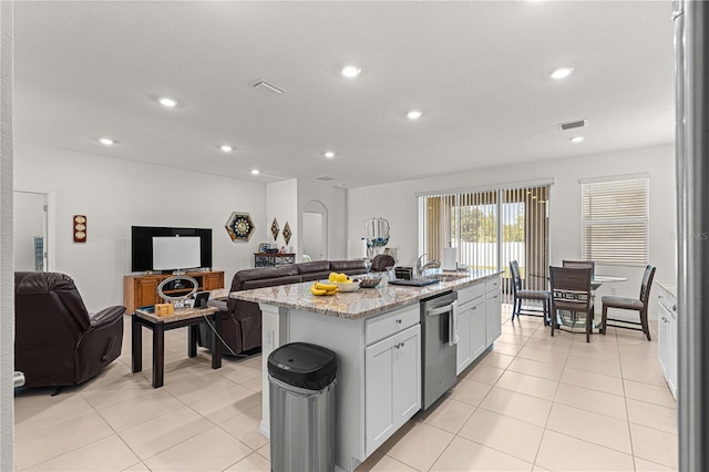 kitchen featuring white cabinetry, sink, a center island with sink, stainless steel dishwasher, and light stone countertops