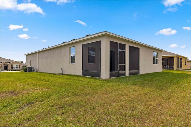 back of property with a lawn, a sunroom, and central AC unit