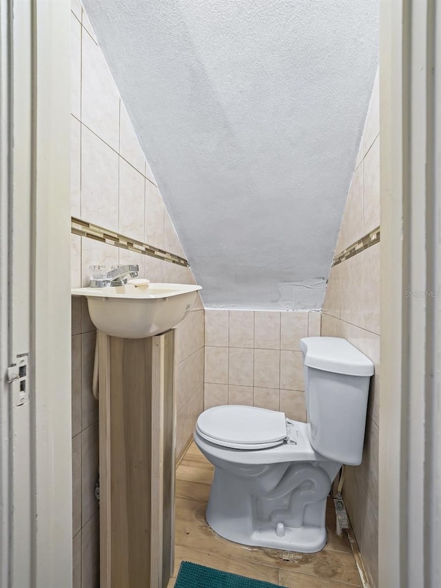 bathroom featuring tile walls, lofted ceiling, wood-type flooring, and toilet