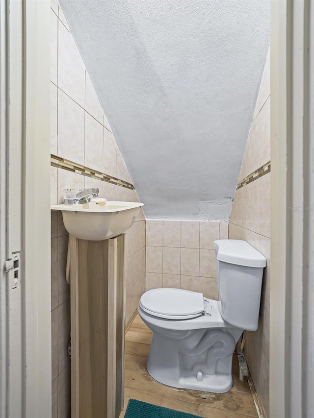 712 SW 10th Ave, Ocala, FL 34471 - bathroom featuring tile walls, lofted ceiling, toilet, a textured ceiling, and wood finished floors