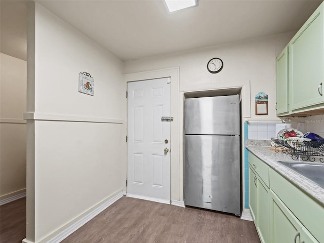 kitchen featuring sink, stainless steel fridge, green cabinetry, and light hardwood / wood-style flooring