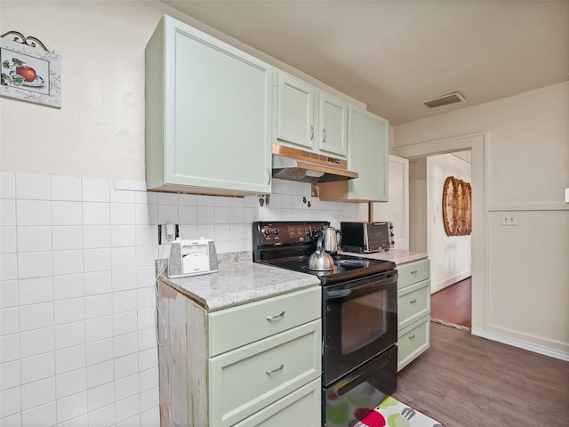 kitchen featuring hardwood / wood-style flooring, black electric range oven, and green cabinets