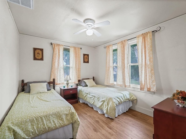 bedroom with multiple windows, hardwood / wood-style floors, crown molding, and ceiling fan