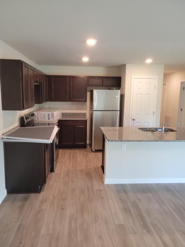 kitchen featuring sink, light hardwood / wood-style flooring, light stone counters, and stainless steel appliances