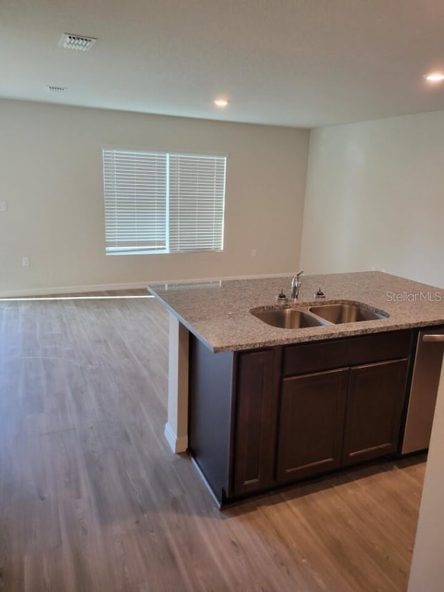 kitchen with light hardwood / wood-style floors, dark brown cabinetry, sink, and light stone counters