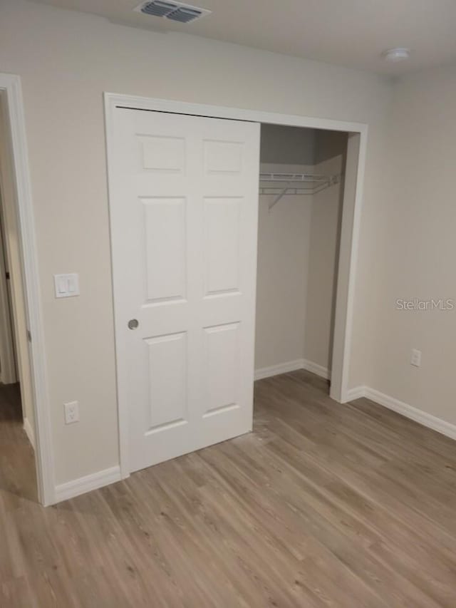 unfurnished bedroom with a closet and light wood-type flooring