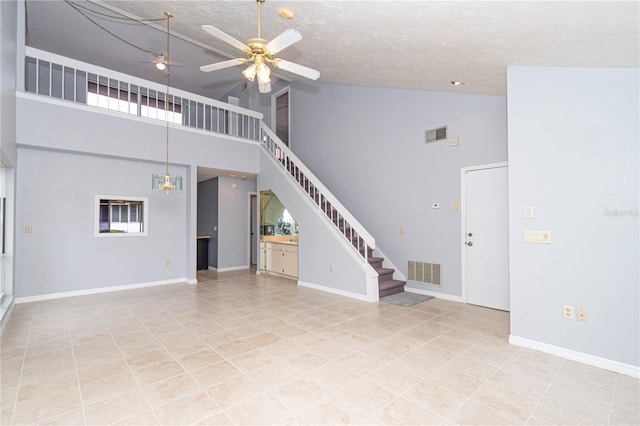 unfurnished living room with light tile patterned flooring, a textured ceiling, high vaulted ceiling, and ceiling fan