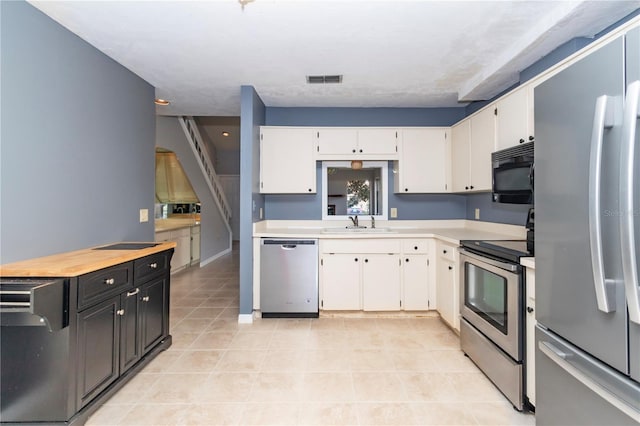 kitchen with light tile patterned floors, stainless steel appliances, sink, and white cabinets