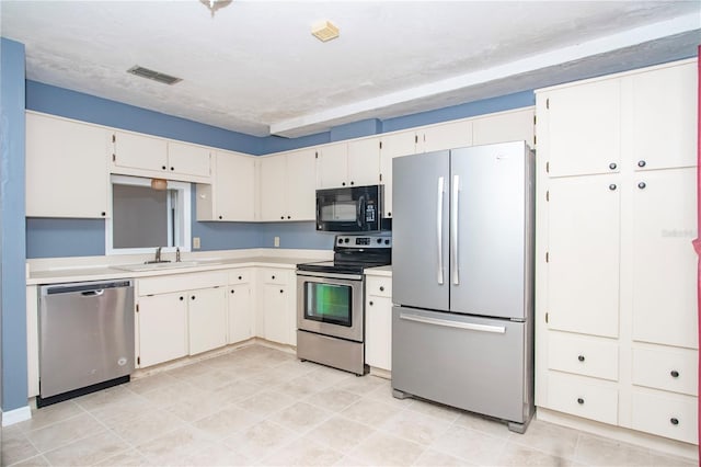 kitchen featuring appliances with stainless steel finishes, white cabinetry, sink, and a textured ceiling