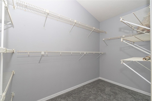 spacious closet featuring dark carpet and lofted ceiling