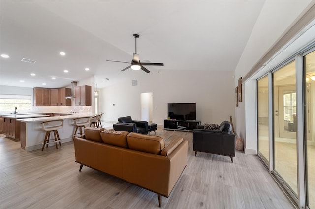 living room featuring light hardwood / wood-style floors, lofted ceiling, and ceiling fan