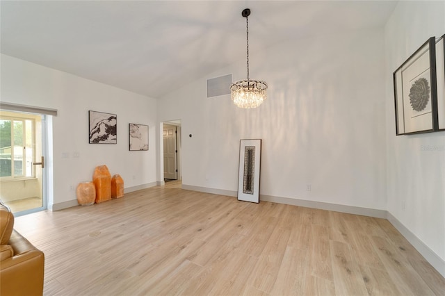 unfurnished living room with light hardwood / wood-style floors, a chandelier, and vaulted ceiling