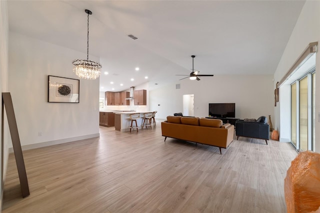 living room featuring light hardwood / wood-style flooring, lofted ceiling, and ceiling fan with notable chandelier