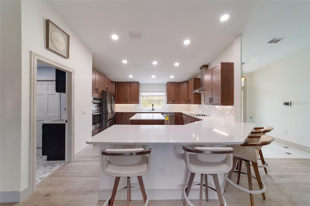 kitchen featuring backsplash, a kitchen breakfast bar, light hardwood / wood-style floors, stainless steel appliances, and decorative light fixtures