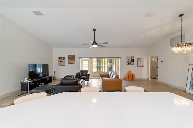 dining space featuring lofted ceiling, light hardwood / wood-style flooring, and ceiling fan with notable chandelier