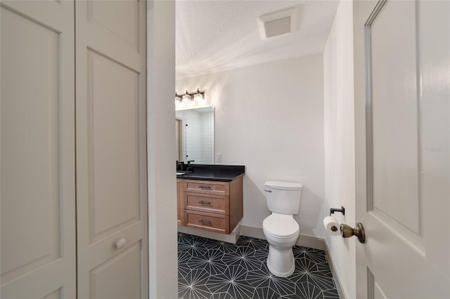 bathroom featuring vanity, toilet, a textured ceiling, and tile patterned flooring