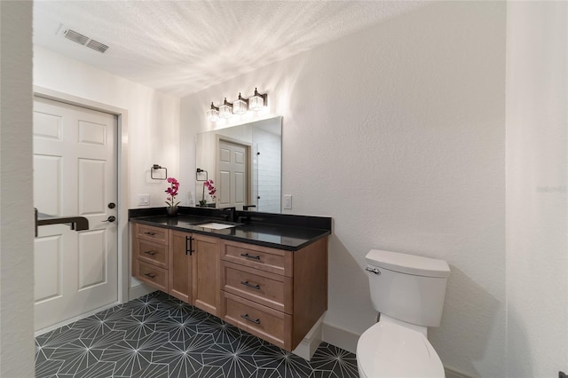 bathroom with vanity, toilet, tile patterned floors, and a textured ceiling