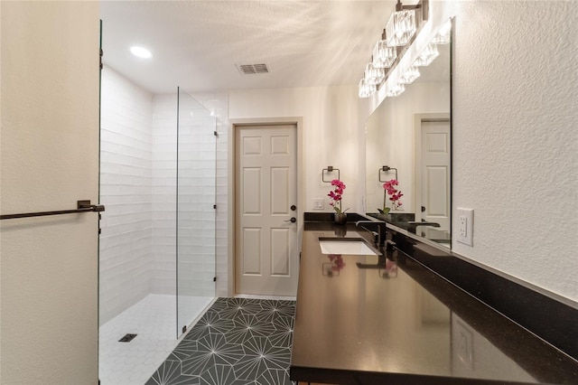 bathroom with tile patterned flooring, sink, and tiled shower