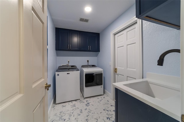 clothes washing area featuring sink, washer and clothes dryer, and cabinets