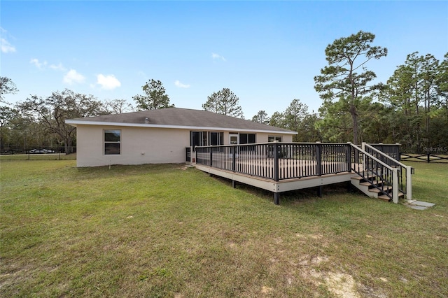 rear view of property featuring a deck and a lawn