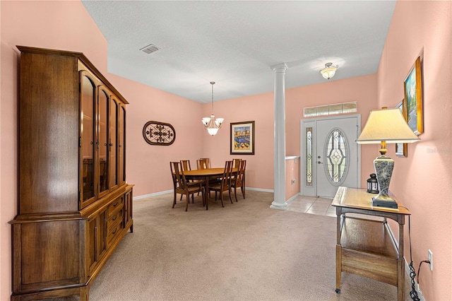 carpeted dining area with a textured ceiling, a chandelier, and decorative columns