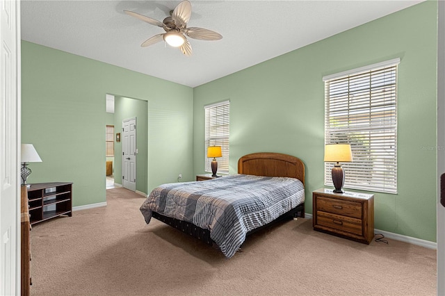 bedroom with ceiling fan, multiple windows, and light colored carpet