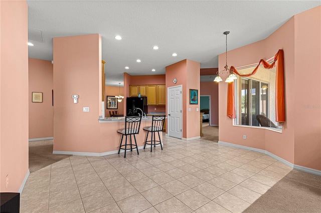 kitchen featuring kitchen peninsula, black fridge, a breakfast bar, a textured ceiling, and light tile patterned flooring